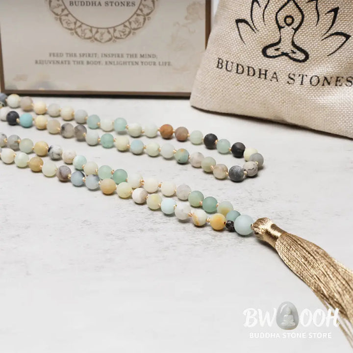 BWOOOH 108 Amazonite Beads Tassel Mala Bracelet on a natural wooden surface, showcasing its serene 6mm blue-green amazonite beads and an intricately woven tassel, reflecting spiritual balance and mindfulness. - View 5