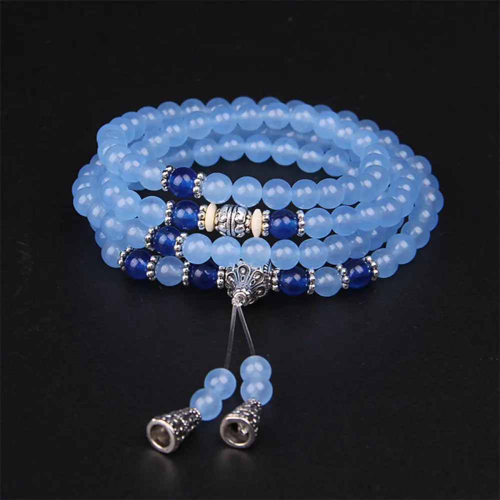 A BWOOOH 108-bead Blue Crystal Healing Mala Bracelet, featuring shimmering 6mm blue crystal beads, styled as a versatile bracelet and necklace. The natural variations in the blue crystals are visible, emphasizing its serene and handcrafted quality, perfect for meditation and spiritual balance.