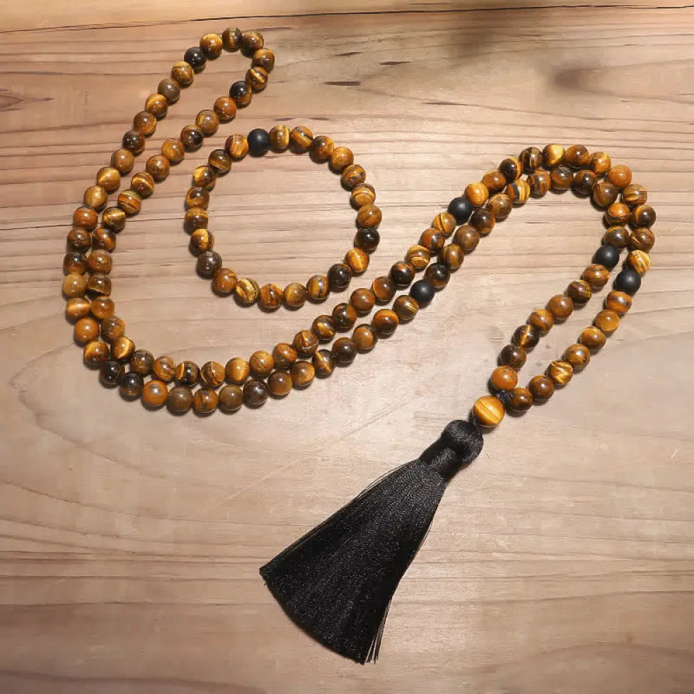 A BWOOOH 108-bead Tiger Eye protection mala bracelet with a matching tassel, showcased on a wrist for meditation and daily spiritual practice, emphasizing courage and positive energy.