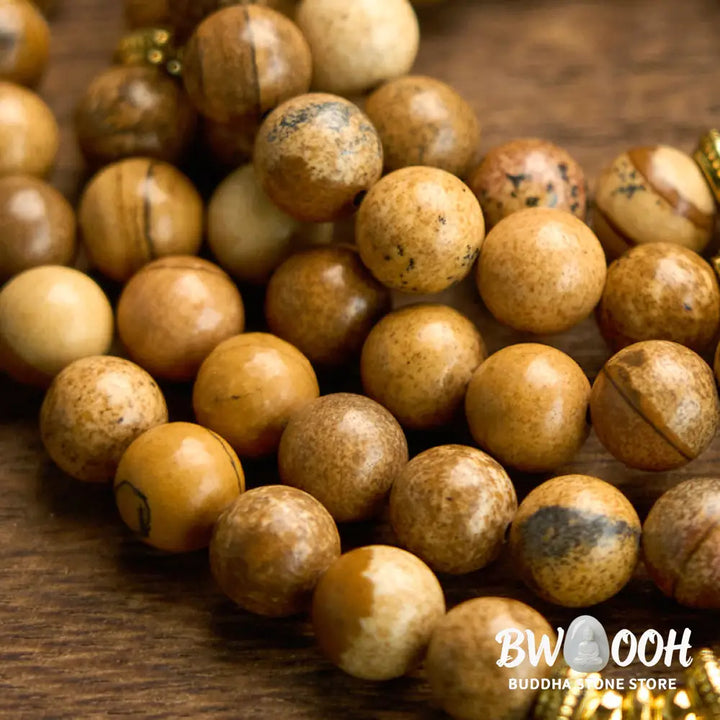 Close-up of BWOOOH 108-bead Picture Jasper Mala bracelet with earthy-toned, 8mm beads and a delicate round lotus-engraved charm, signifying courage and spiritual grounding for meditation. - View 6