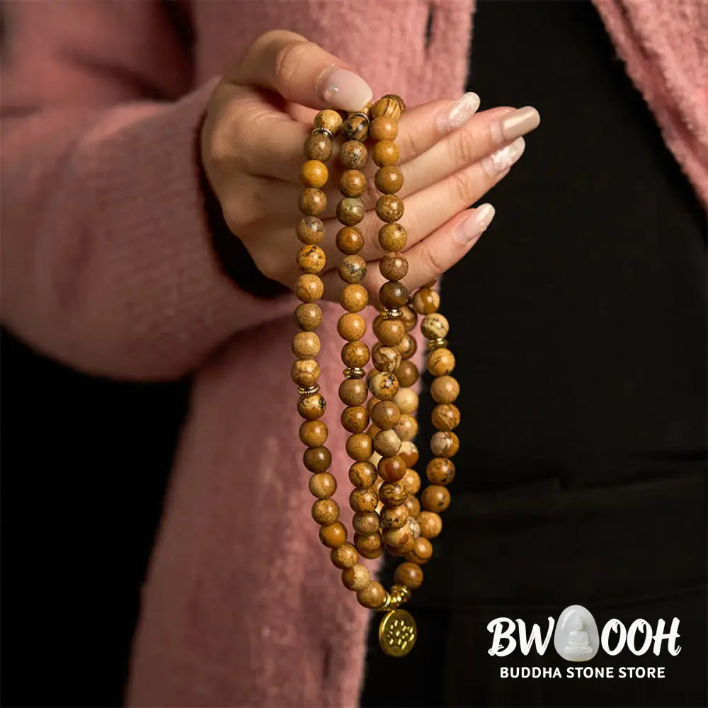 Close-up of BWOOOH 108-bead Picture Jasper Mala bracelet with earthy-toned, 8mm beads and a delicate round lotus-engraved charm, signifying courage and spiritual grounding for meditation. - View 4