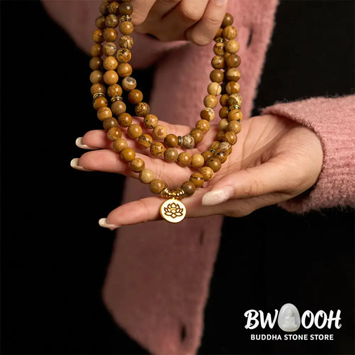 Close-up of BWOOOH 108-bead Picture Jasper Mala bracelet with earthy-toned, 8mm beads and a delicate round lotus-engraved charm, signifying courage and spiritual grounding for meditation. - View 5