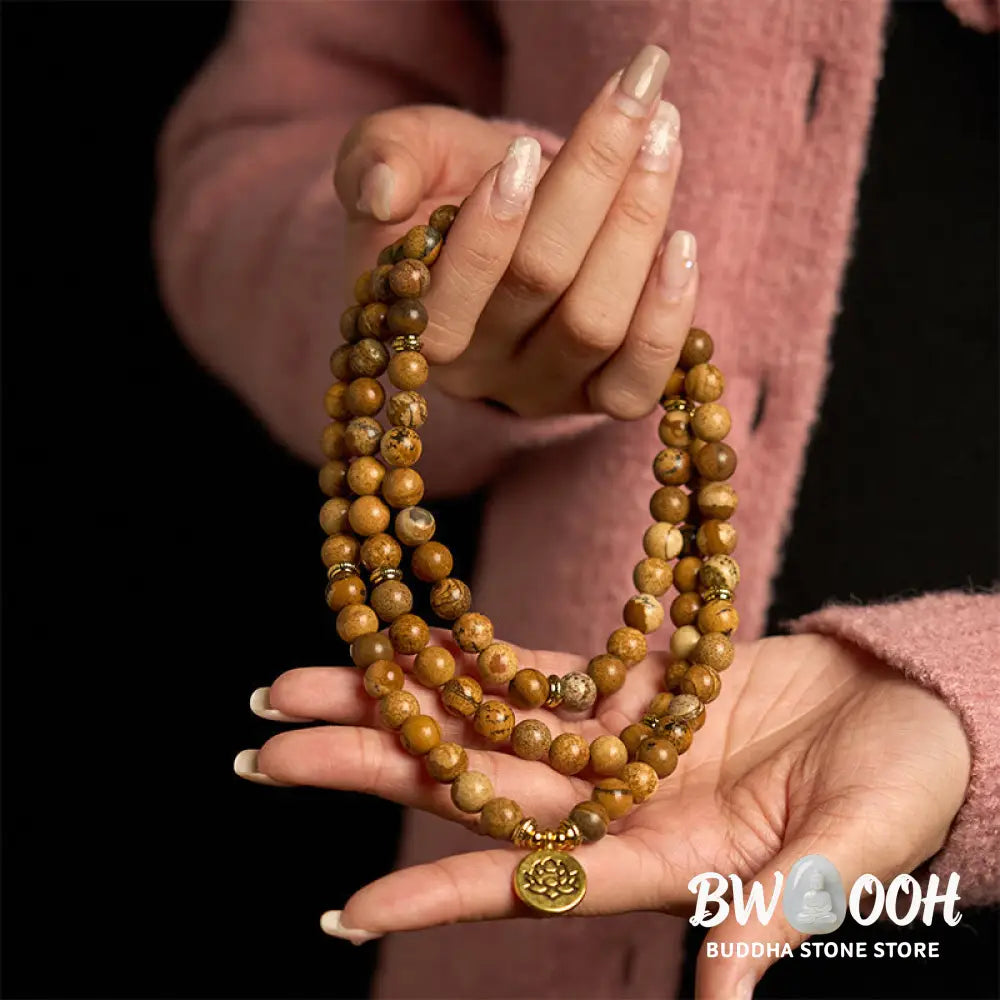 Close-up of BWOOOH 108-bead Picture Jasper Mala bracelet with earthy-toned, 8mm beads and a delicate round lotus-engraved charm, signifying courage and spiritual grounding for meditation. - View 3