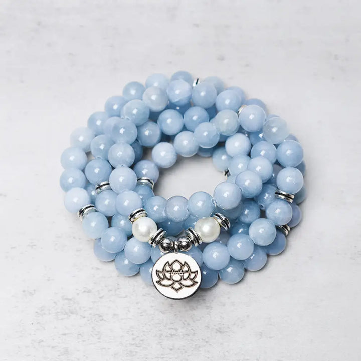 A close-up of the BWOOOH 108-bead Aquamarine Mala healing bracelet, featuring hand-grinded 8mm blue aquamarine crystals, aesthetic circle spacers, and a central aluminum lotus engraving, designed for meditation and spiritual balance.