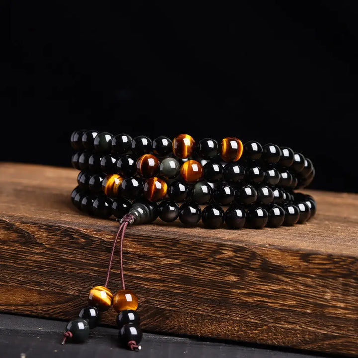 BWOOOH 108 Mala Beads crafted from polished Black Obsidian and shimmering Ice Obsidian, symbolizing energy protection and inner fulfillment, designed for meditation and mindfulness, photographed on a serene, textured surface.