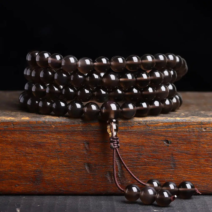 BWOOOH 108 Mala Beads crafted from polished Black Obsidian and shimmering Ice Obsidian, symbolizing energy protection and inner fulfillment, designed for meditation and mindfulness, photographed on a serene, textured surface. - View 14