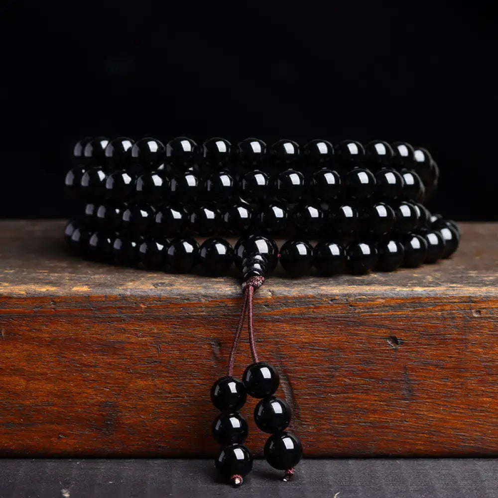 BWOOOH 108 Mala Beads crafted from polished Black Obsidian and shimmering Ice Obsidian, symbolizing energy protection and inner fulfillment, designed for meditation and mindfulness, photographed on a serene, textured surface. - View 8
