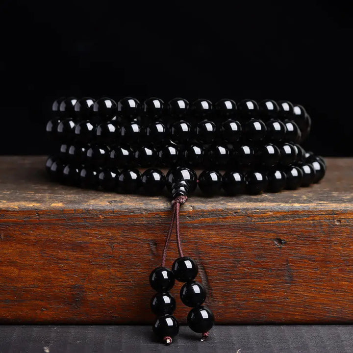 BWOOOH 108 Mala Beads crafted from polished Black Obsidian and shimmering Ice Obsidian, symbolizing energy protection and inner fulfillment, designed for meditation and mindfulness, photographed on a serene, textured surface. - View 8
