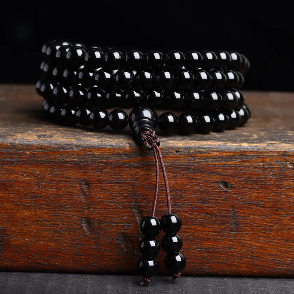 BWOOOH 108 Mala Beads crafted from polished Black Obsidian and shimmering Ice Obsidian, symbolizing energy protection and inner fulfillment, designed for meditation and mindfulness, photographed on a serene, textured surface. - View 10