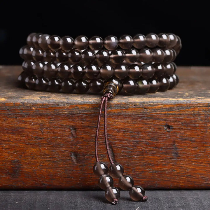 BWOOOH 108 Mala Beads crafted from polished Black Obsidian and shimmering Ice Obsidian, symbolizing energy protection and inner fulfillment, designed for meditation and mindfulness, photographed on a serene, textured surface. - View 12