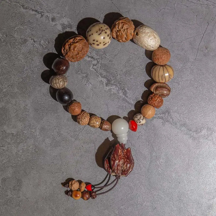 A close-up of the BWOOOH 108 Bodhi Seed Mala Bracelet, showcasing naturally varied seeds, a prominent guru bead, and a delicate lotus tassel, arranged for meditation or wrist wear. - View 6