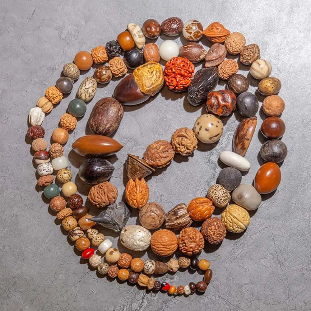 A close-up of the BWOOOH 108 Bodhi Seed Mala Bracelet, showcasing naturally varied seeds, a prominent guru bead, and a delicate lotus tassel, arranged for meditation or wrist wear.