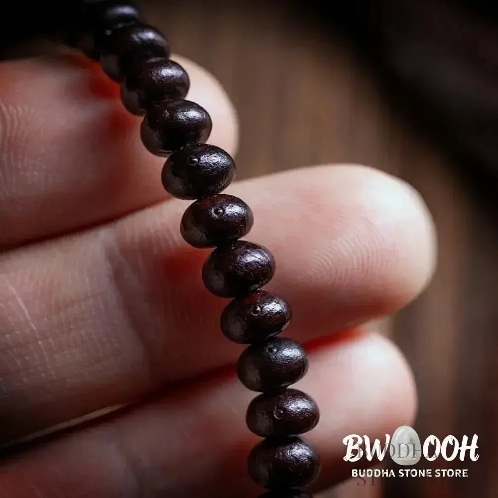 A close-up of the BWOOOH 108 Mala Bracelet, showcasing polished red Bowl Bodhi seeds, each with a distinct &