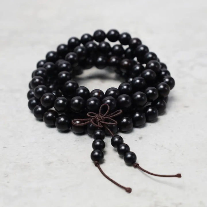 A close-up of the BWOOOH 108 mala beads bracelet, showcasing smooth, aromatic sandalwood interspersed with dark ebony, rich rosewood, and stabilizing wenge wood. The elastic design highlights the natural wood grain, perfect for meditation, prayer, and achieving daily spiritual balance. - View 8
