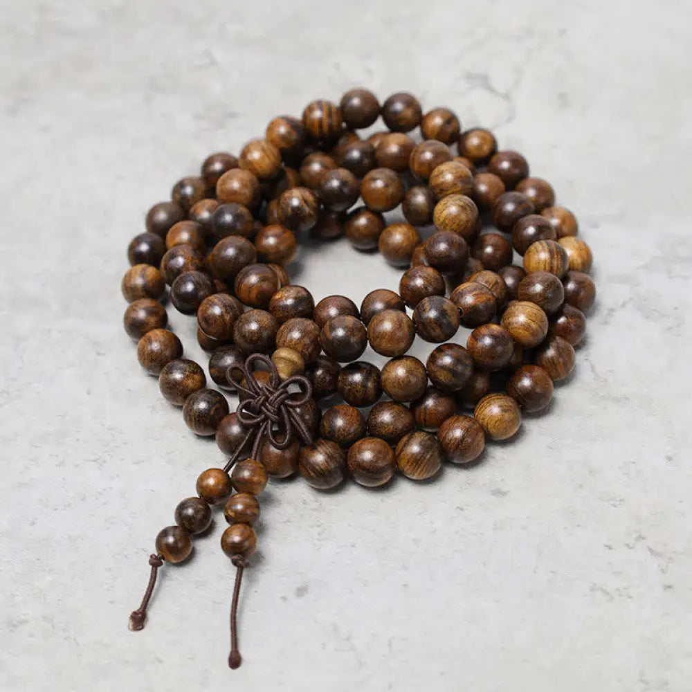 A close-up of the BWOOOH 108 mala beads bracelet, showcasing smooth, aromatic sandalwood interspersed with dark ebony, rich rosewood, and stabilizing wenge wood. The elastic design highlights the natural wood grain, perfect for meditation, prayer, and achieving daily spiritual balance.