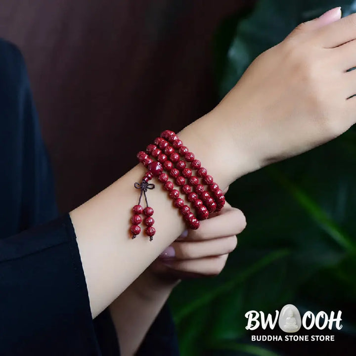 A BWOOOH Cinnabar 108 Mala Beads Blessing Bracelet, showcasing deeply engraved Om Mani Padme Hum mantra patterns on each bead, symbolizing spiritual protection and focus. - View 11