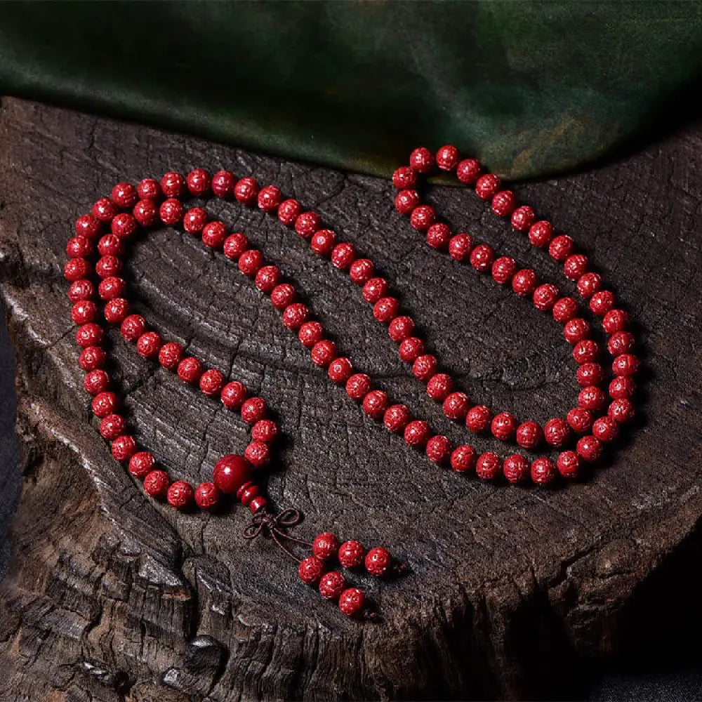 A BWOOOH Cinnabar 108 Mala Beads Blessing Bracelet, showcasing deeply engraved Om Mani Padme Hum mantra patterns on each bead, symbolizing spiritual protection and focus. - View 7