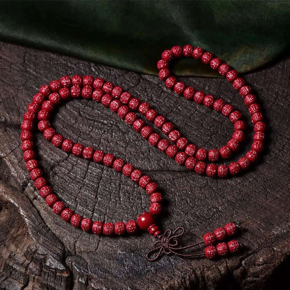A BWOOOH Cinnabar 108 Mala Beads Blessing Bracelet, showcasing deeply engraved Om Mani Padme Hum mantra patterns on each bead, symbolizing spiritual protection and focus. - View 12
