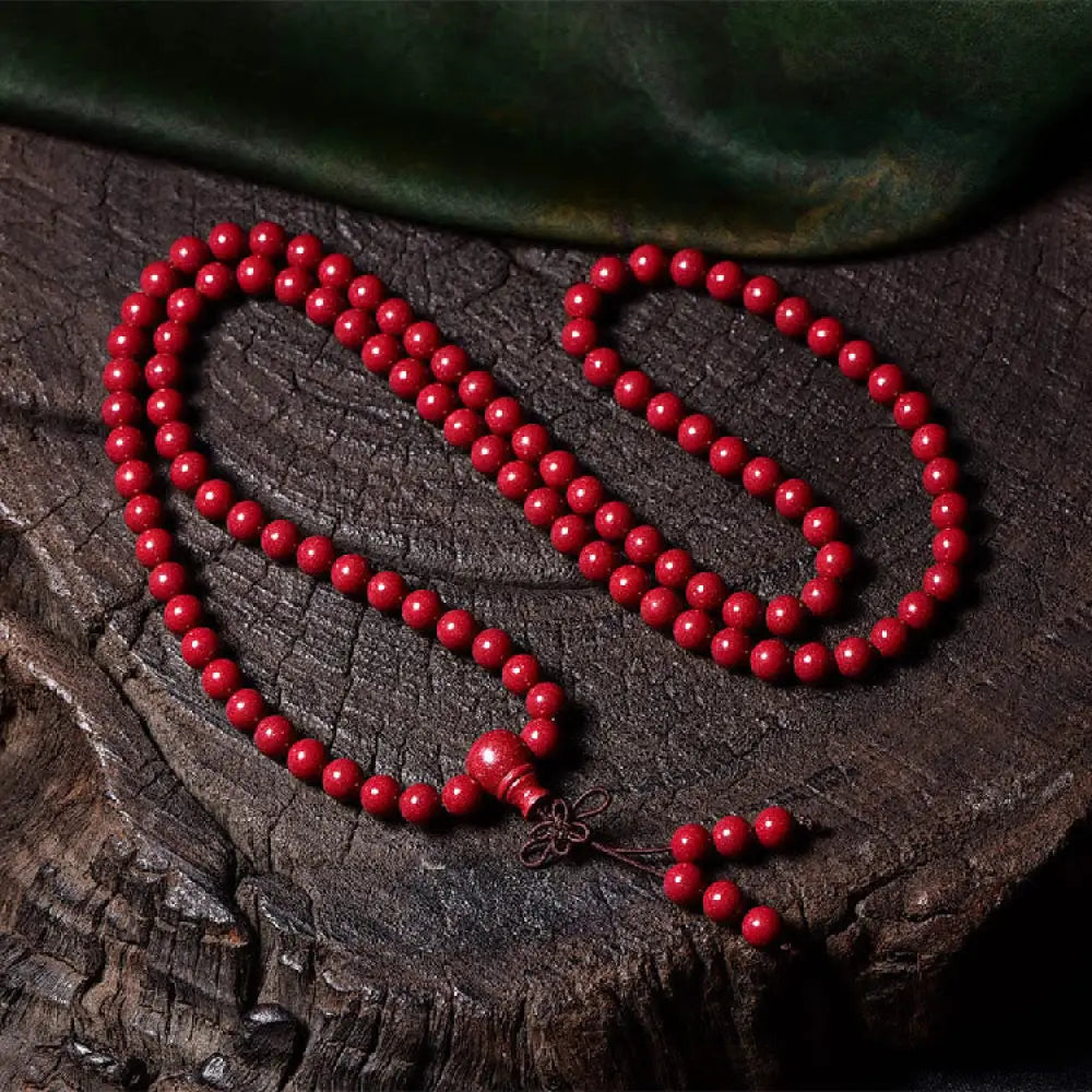 A BWOOOH Cinnabar 108 Mala Beads Blessing Bracelet, showcasing deeply engraved Om Mani Padme Hum mantra patterns on each bead, symbolizing spiritual protection and focus. - View 16