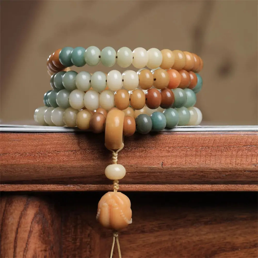 Close-up of BWOOOH 108 gradient Bodhi Seed mala beads, each hand-engraved with a subtle Buddha hand symbol, strung on an elastic peace bracelet, showcasing unique dark-speckled textures.