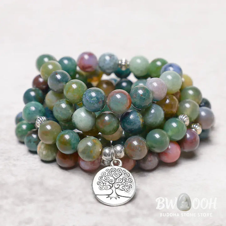 A BWOOOH 108 Indian Agate Mala Beads bracelet, featuring a prominent OM symbol charm, a serene Lotus charm, and a detailed Tree of Life charm, all strung on a premium elastic band, against a minimalist backdrop. - View 9