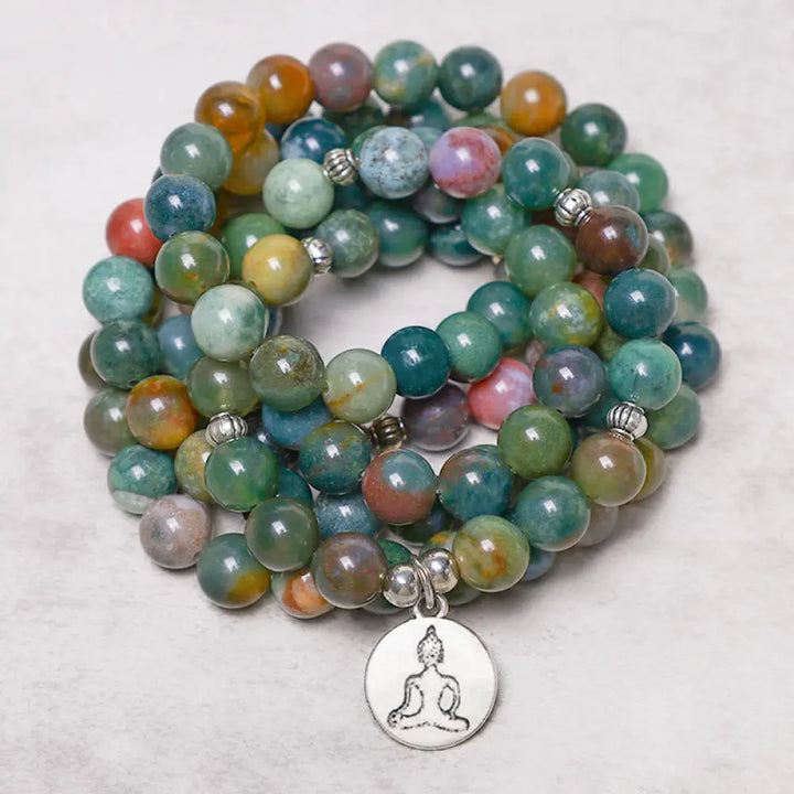 A BWOOOH 108 Indian Agate Mala Beads bracelet, featuring a prominent OM symbol charm, a serene Lotus charm, and a detailed Tree of Life charm, all strung on a premium elastic band, against a minimalist backdrop. - View 5