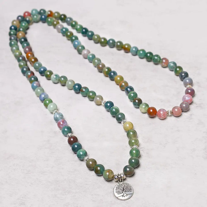 A BWOOOH 108 Indian Agate Mala Beads bracelet, featuring a prominent OM symbol charm, a serene Lotus charm, and a detailed Tree of Life charm, all strung on a premium elastic band, against a minimalist backdrop. - View 7