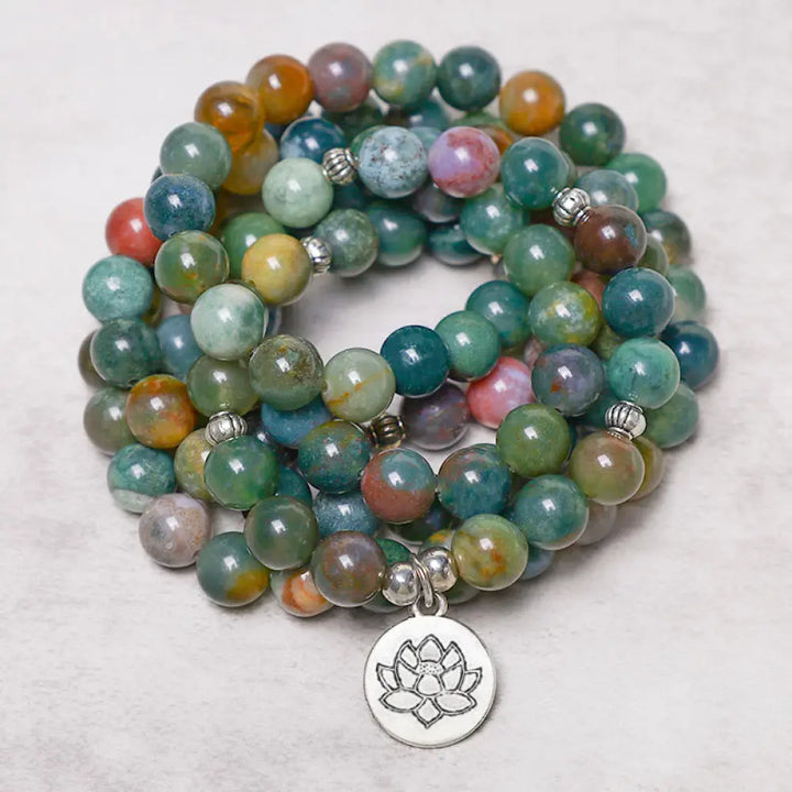 A BWOOOH 108 Indian Agate Mala Beads bracelet, featuring a prominent OM symbol charm, a serene Lotus charm, and a detailed Tree of Life charm, all strung on a premium elastic band, against a minimalist backdrop.
