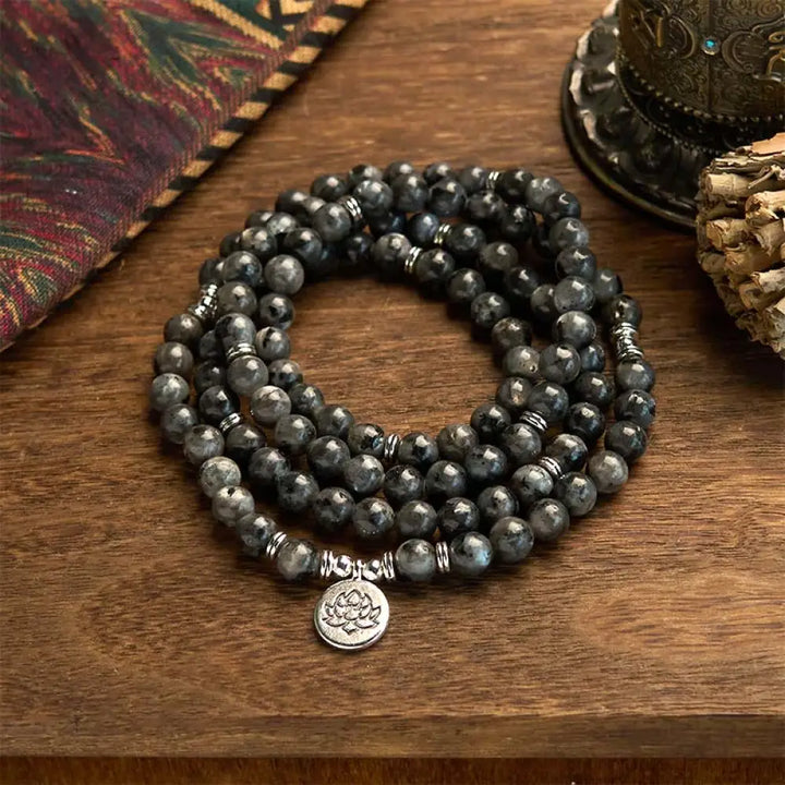 BWOOOH 108-bead multi-layer Black Glitter Stone Mala bracelet with engraved lotus pendant, symbolizing purity and strength, on a neutral background.