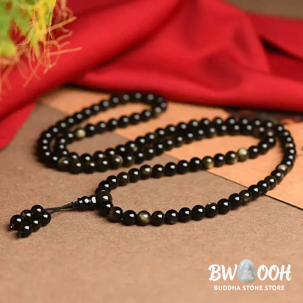 A close-up of the BWOOOH 108 Mala Beads Natural Gold Sheen Obsidian Wealth Bracelet, showcasing the distinctive golden sheen and polished dark beads, worn on a wrist. - View 4