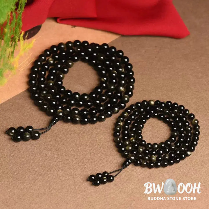 A close-up of the BWOOOH 108 Mala Beads Natural Gold Sheen Obsidian Wealth Bracelet, showcasing the distinctive golden sheen and polished dark beads, worn on a wrist. - View 6
