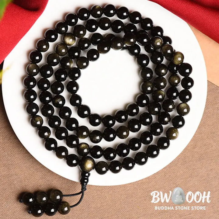 A close-up of the BWOOOH 108 Mala Beads Natural Gold Sheen Obsidian Wealth Bracelet, showcasing the distinctive golden sheen and polished dark beads, worn on a wrist. - View 8