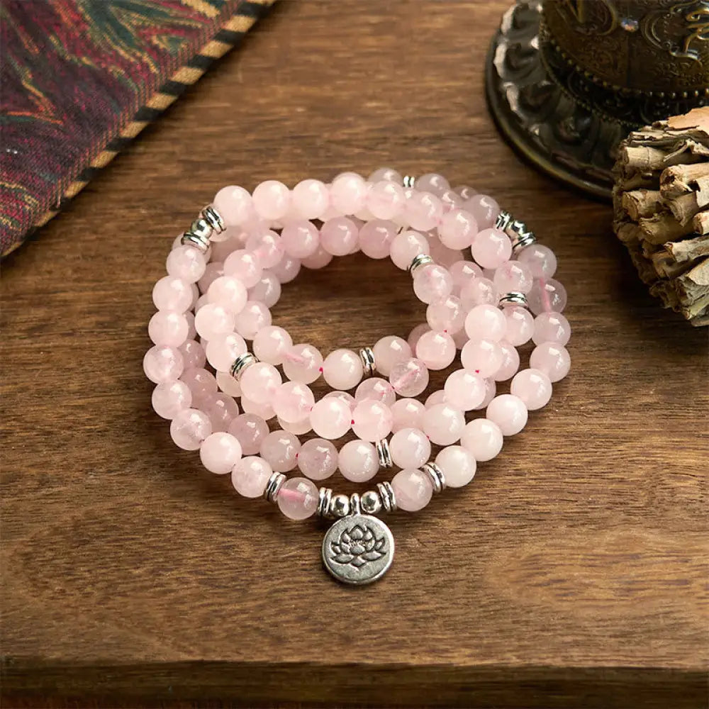 A BWOOOH Rose Quartz 108 mala bead bracelet with 8mm natural stones, featuring a round engraved lotus peace symbol pendant on a premium elastic string, ideal for meditation and emotional balance.
