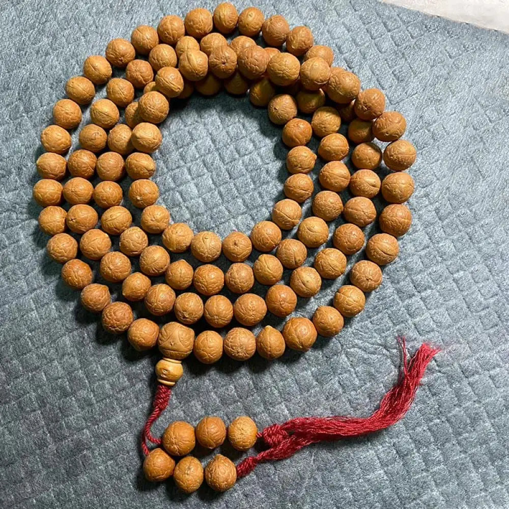 BWOOOH 108-bead Nepal Bodhi Seed Mala bracelet featuring varied 11-13mm dark-speckled seeds on premium string, with a symbolic tassel, designed for meditation and daily spiritual awareness.