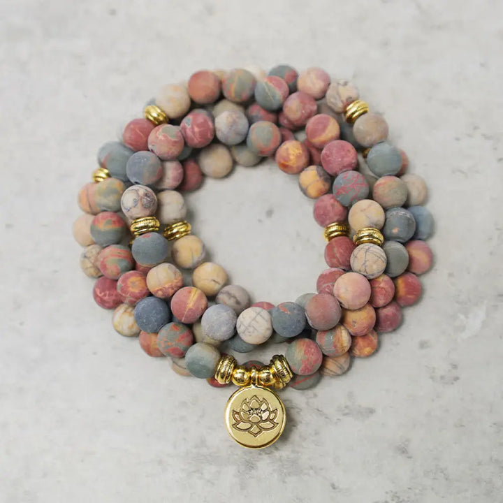 BWOOOH 108 Mala beads bracelet featuring naturally textured 8mm Picasso Jasper stones, accented with a delicate Lotus Symbol charm, symbolizing courage and spiritual resilience on an elastic band.