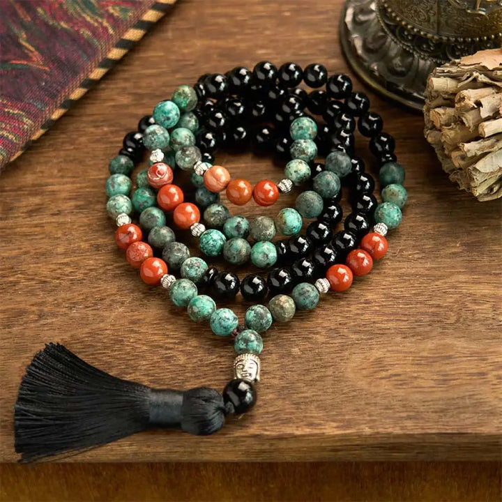 BWOOOH 108 Mala Protection Bracelet featuring 8mm natural Black Onyx, Red Jasper, and Turquoise beads, with a detailed Buddha Head charm and traditional tassel, displayed as a meditation accessory for spiritual balance and personal empowerment.