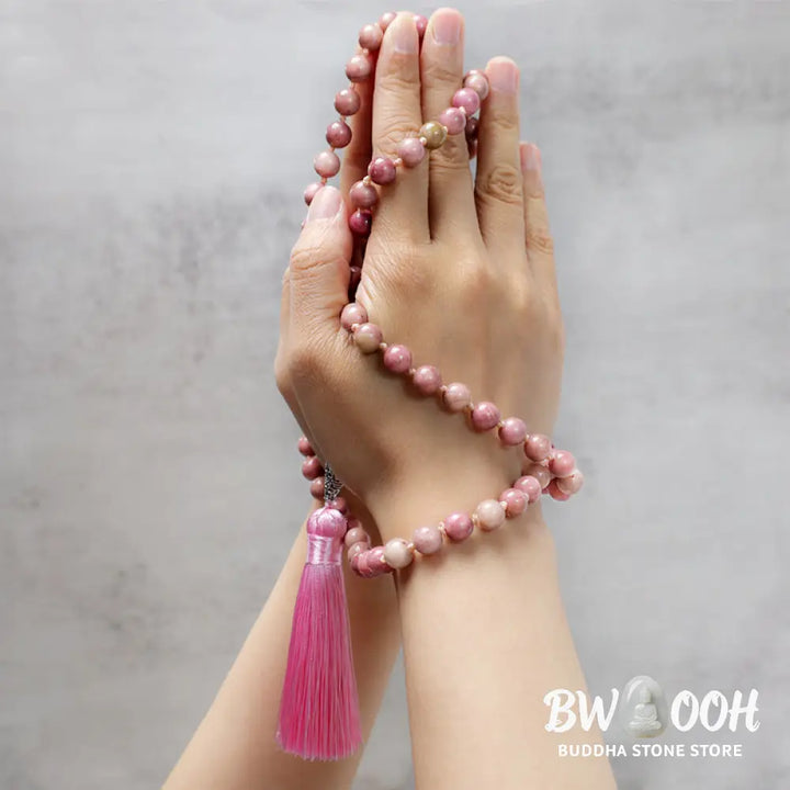 BWOOOH 108-bead Rhodonite Mala, a meditation bracelet or necklace featuring 8MM polished, natural pink rhodonite beads known for loving energy and healing properties, displayed on a tranquil surface. - View 3