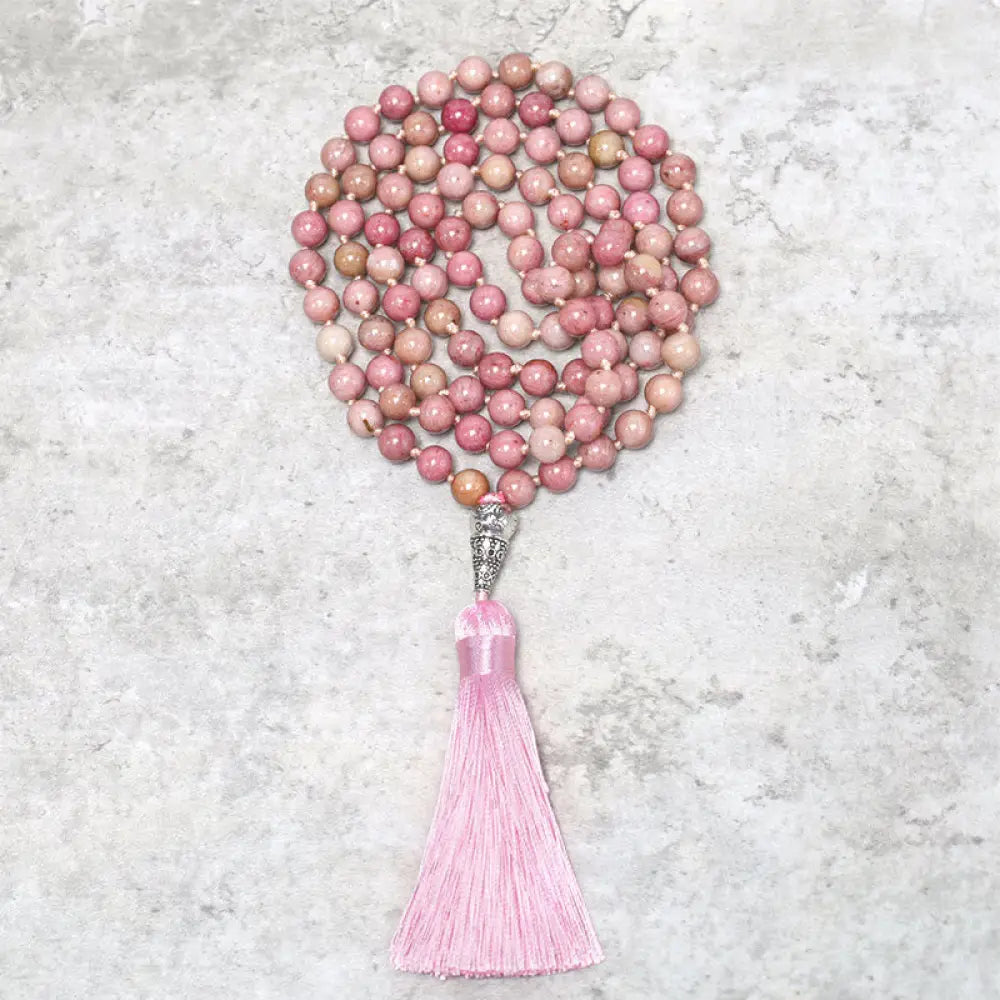 BWOOOH 108-bead Rhodonite Mala, a meditation bracelet or necklace featuring 8MM polished, natural pink rhodonite beads known for loving energy and healing properties, displayed on a tranquil surface.