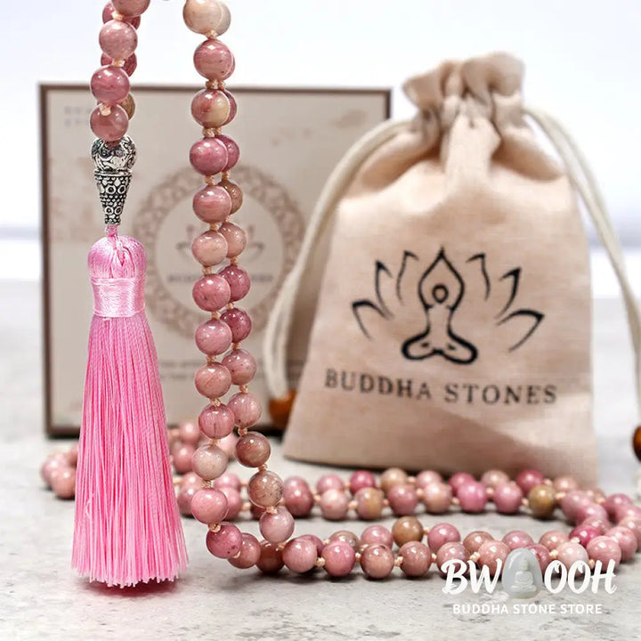 BWOOOH 108-bead Rhodonite Mala, a meditation bracelet or necklace featuring 8MM polished, natural pink rhodonite beads known for loving energy and healing properties, displayed on a tranquil surface. - View 6