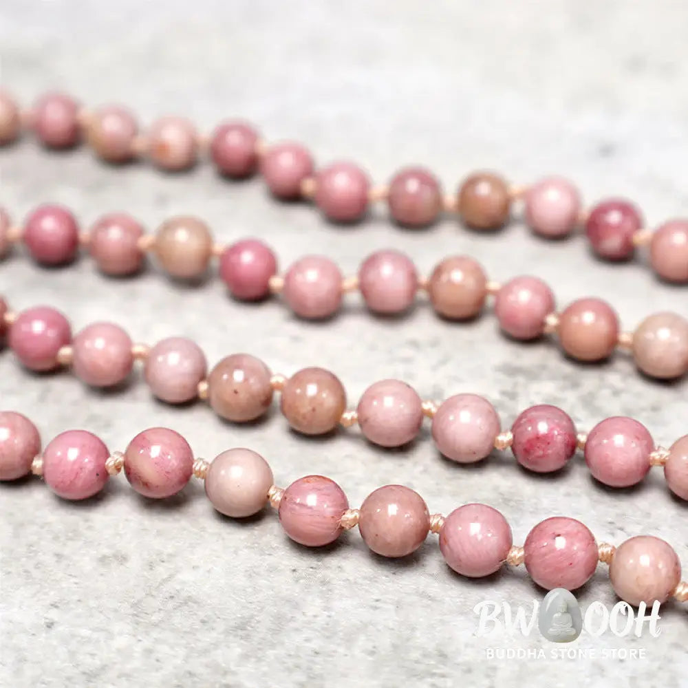 BWOOOH 108-bead Rhodonite Mala, a meditation bracelet or necklace featuring 8MM polished, natural pink rhodonite beads known for loving energy and healing properties, displayed on a tranquil surface. - View 5