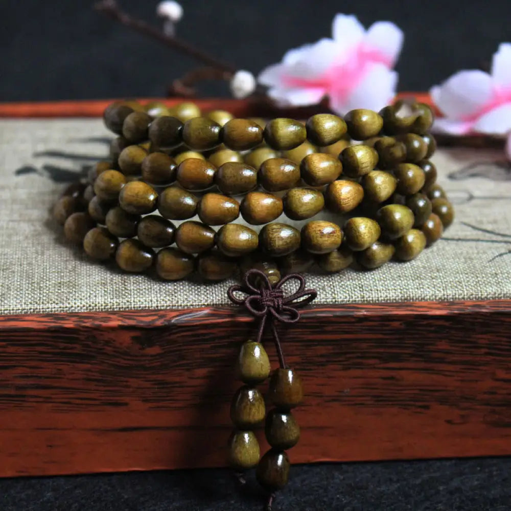 A BWOOOH 108 Mala Teardrop Beads Protection Bracelet, crafted from natural Phoebe Zhennan Wood, showcasing its unique grain and spiritual essence on a clean, mindful background. The premium elastic string is visible.