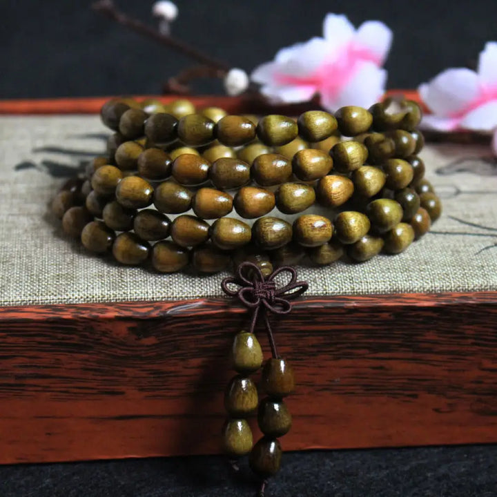 A BWOOOH 108 Mala Teardrop Beads Protection Bracelet, crafted from natural Phoebe Zhennan Wood, showcasing its unique grain and spiritual essence on a clean, mindful background. The premium elastic string is visible.