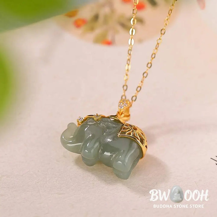 A close-up of the BWOOOH 925 Sterling Silver gold-plated elephant pendant, intricately carved and holding a vibrant jade stone, against a minimalist backdrop, highlighting its 45cm chain. - View 5