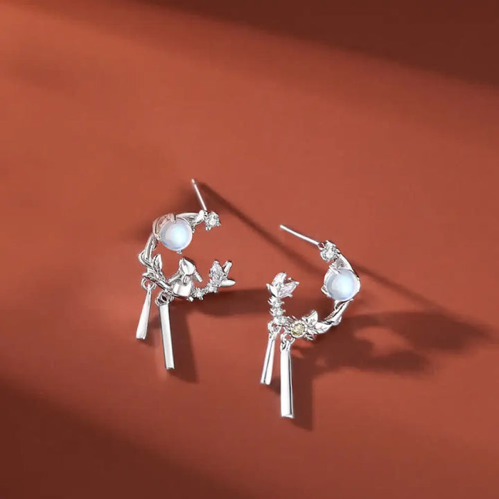 A complete BWOOOH 925 Sterling Silver Year of the Rabbit Moonstone Moon Flower Pattern Necklace, Pendant, Bracelet, and Earrings set on a serene, reflective surface. Each piece features natural moonstone with its ethereal blue adularescence, set in intricate silver moon flower motifs. The pendant prominently displays the rabbit emblem, symbolizing peace, elegance, and good fortune, evoking spiritual balance. - View 9