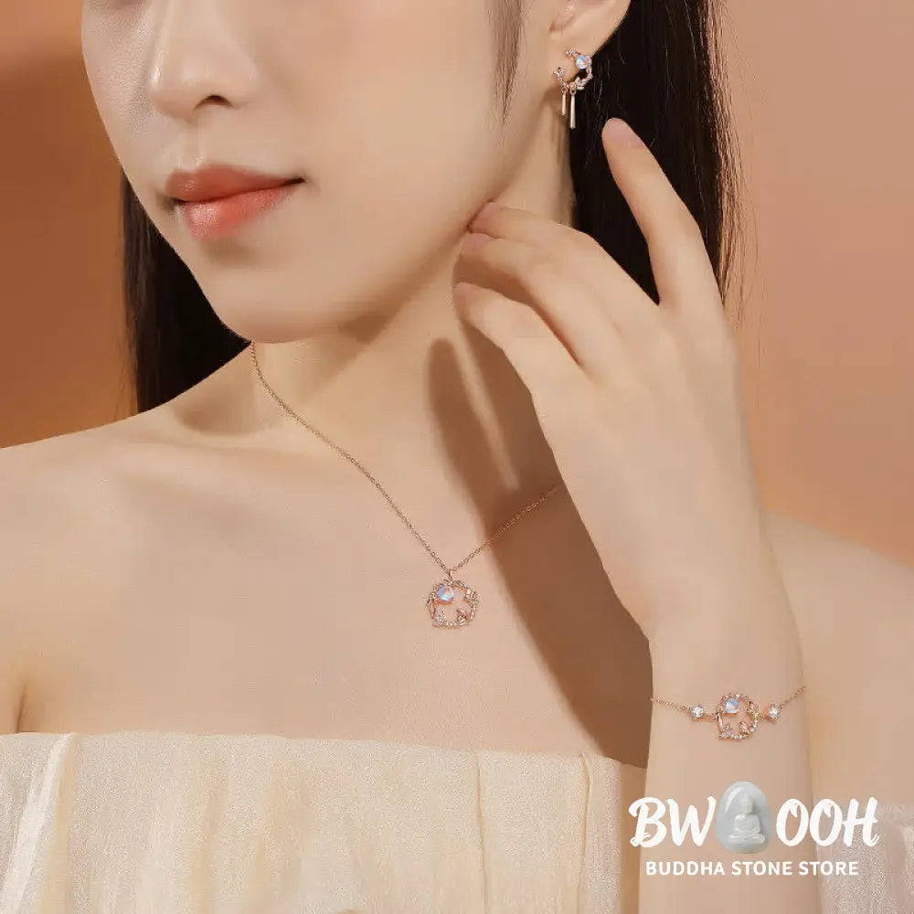 A complete BWOOOH 925 Sterling Silver Year of the Rabbit Moonstone Moon Flower Pattern Necklace, Pendant, Bracelet, and Earrings set on a serene, reflective surface. Each piece features natural moonstone with its ethereal blue adularescence, set in intricate silver moon flower motifs. The pendant prominently displays the rabbit emblem, symbolizing peace, elegance, and good fortune, evoking spiritual balance. - View 2