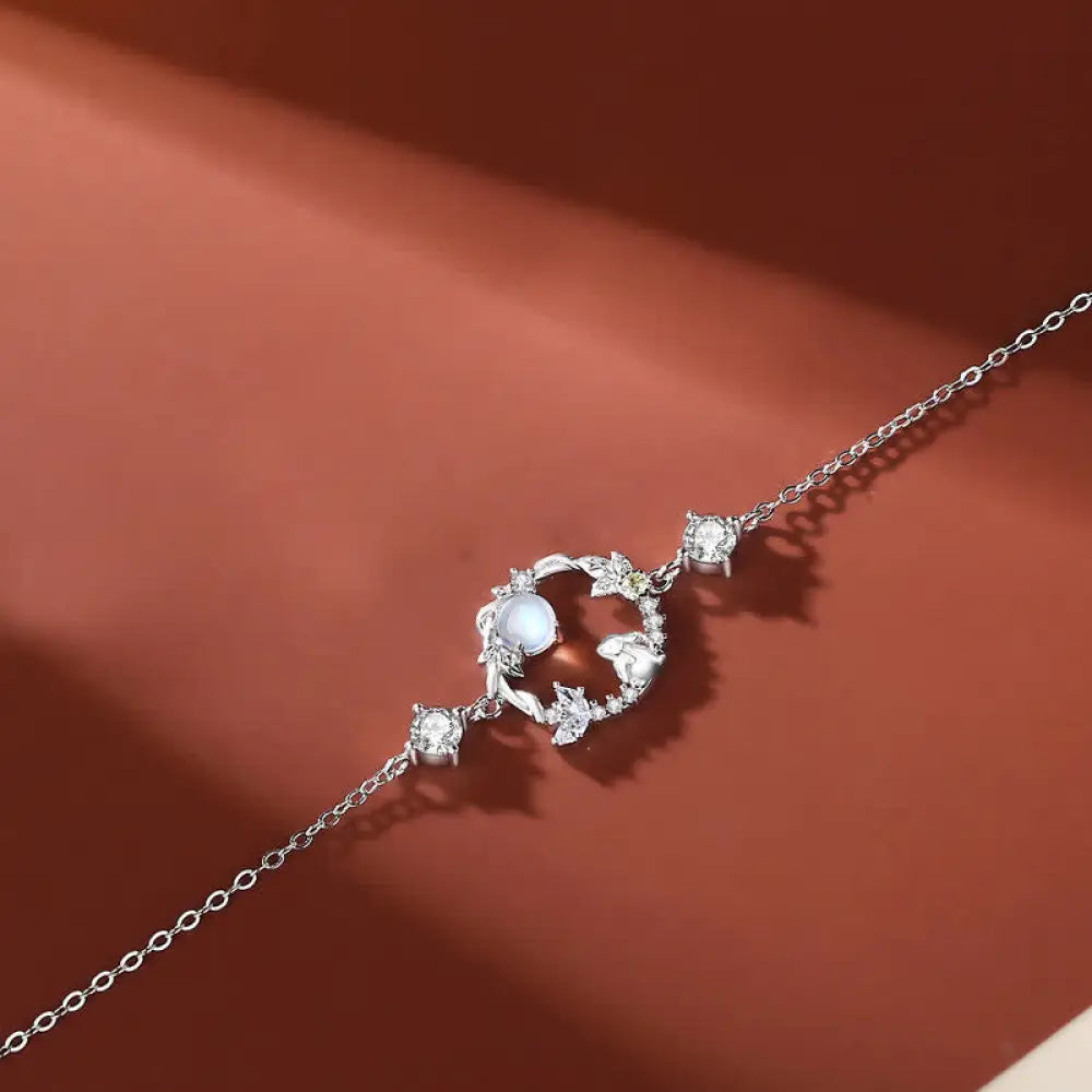A complete BWOOOH 925 Sterling Silver Year of the Rabbit Moonstone Moon Flower Pattern Necklace, Pendant, Bracelet, and Earrings set on a serene, reflective surface. Each piece features natural moonstone with its ethereal blue adularescence, set in intricate silver moon flower motifs. The pendant prominently displays the rabbit emblem, symbolizing peace, elegance, and good fortune, evoking spiritual balance. - View 7
