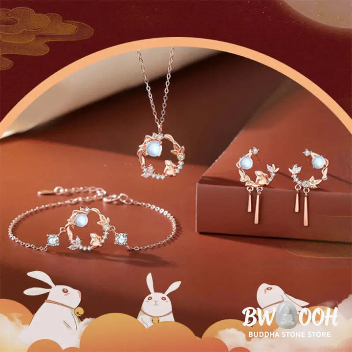 A complete BWOOOH 925 Sterling Silver Year of the Rabbit Moonstone Moon Flower Pattern Necklace, Pendant, Bracelet, and Earrings set on a serene, reflective surface. Each piece features natural moonstone with its ethereal blue adularescence, set in intricate silver moon flower motifs. The pendant prominently displays the rabbit emblem, symbolizing peace, elegance, and good fortune, evoking spiritual balance. - View 10