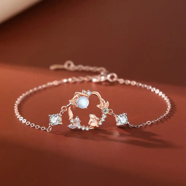 A complete BWOOOH 925 Sterling Silver Year of the Rabbit Moonstone Moon Flower Pattern Necklace, Pendant, Bracelet, and Earrings set on a serene, reflective surface. Each piece features natural moonstone with its ethereal blue adularescence, set in intricate silver moon flower motifs. The pendant prominently displays the rabbit emblem, symbolizing peace, elegance, and good fortune, evoking spiritual balance. - View 6