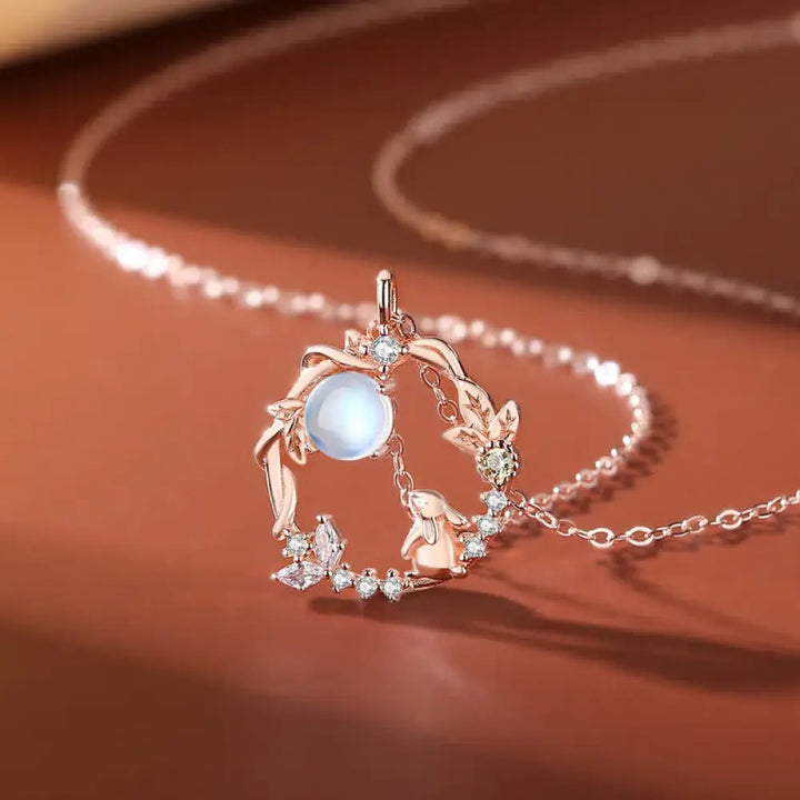 A complete BWOOOH 925 Sterling Silver Year of the Rabbit Moonstone Moon Flower Pattern Necklace, Pendant, Bracelet, and Earrings set on a serene, reflective surface. Each piece features natural moonstone with its ethereal blue adularescence, set in intricate silver moon flower motifs. The pendant prominently displays the rabbit emblem, symbolizing peace, elegance, and good fortune, evoking spiritual balance.