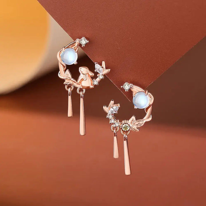 A complete BWOOOH 925 Sterling Silver Year of the Rabbit Moonstone Moon Flower Pattern Necklace, Pendant, Bracelet, and Earrings set on a serene, reflective surface. Each piece features natural moonstone with its ethereal blue adularescence, set in intricate silver moon flower motifs. The pendant prominently displays the rabbit emblem, symbolizing peace, elegance, and good fortune, evoking spiritual balance. - View 8